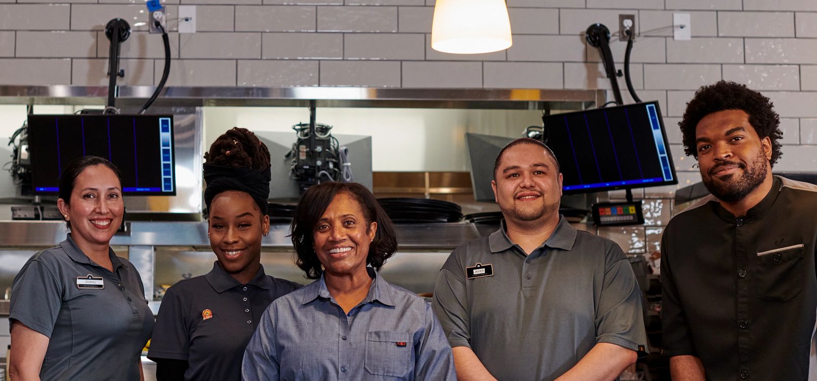 Three Denny's restaurant staff members posing together in their uniforms