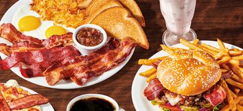 Close-up of Denny's Baconalia menu with triple bacon sampler, bacon obsession burger, bacon pancakes, bacon milkshake, and coffee