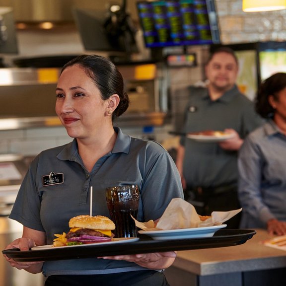 Female server picking up food from the kitchen