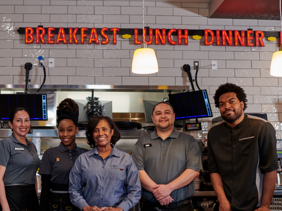 Employees smiling in the kitchen as they pose for a photo